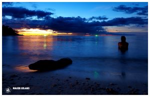 Noc na plaży w Koh Phangan w Tajlandii , malowniczy zachód słońca i magda siedząca na brzegu, konar drzewa, chmury na horyzoncie, zmierzch,