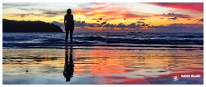 plaża z zachodem słońca, fale morskie, piasek mokry, dziewczyna stoi i patrzy na zachód słońca, bardzo kolorowo