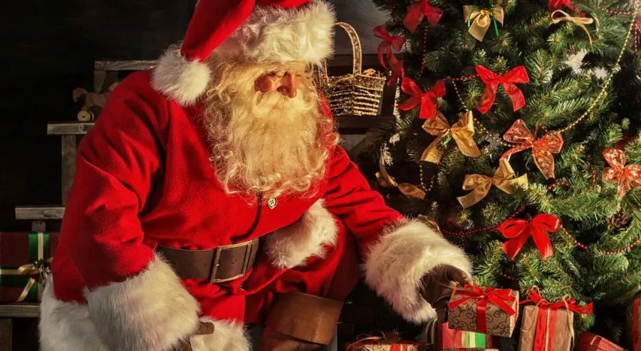 Swięty Mikołaj z prezentami pod choinką