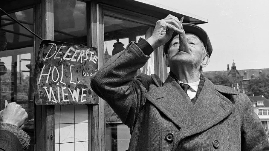 Mężczyzna jedzący śledzia na ulicy