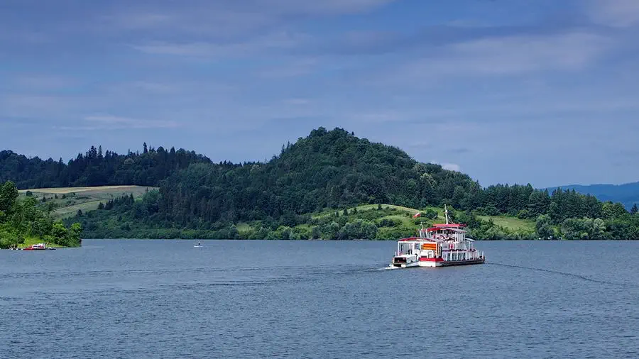 Zamek w Czorsztynie na wzniesieniu ponad jeziorem. Statek na jeziorze.