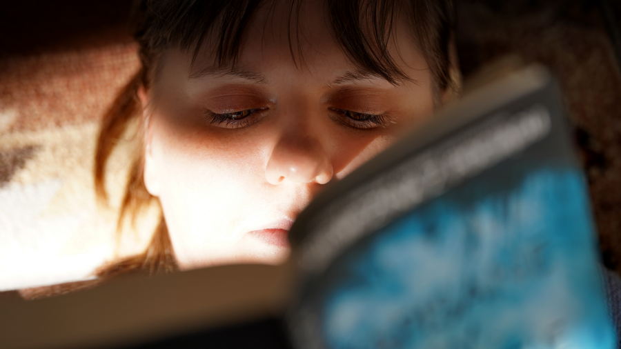 Magdalena Kizewska z książką w bibliotece